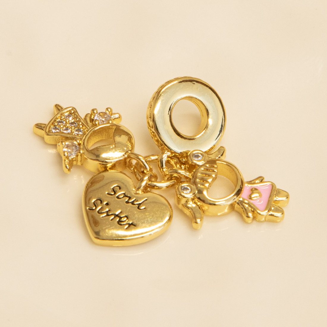 Gold charms on a white dish: a Soul Sister heart and two little girl charms with sparkling stones.