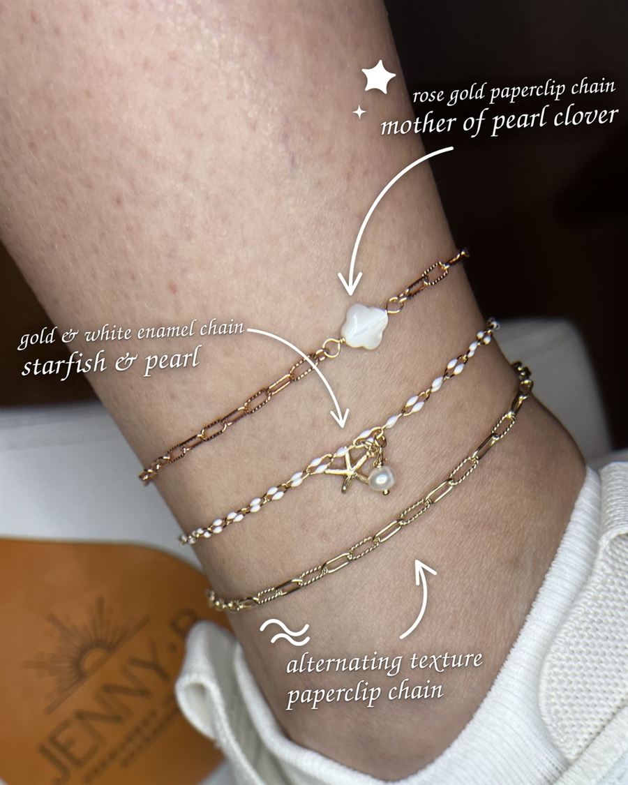 Three gold anklets stacked: rose gold paperclip chain with a mother of pearl clover, gold and white enamel chain with a starfish and pearl, and an alternating texture paperclip chain.