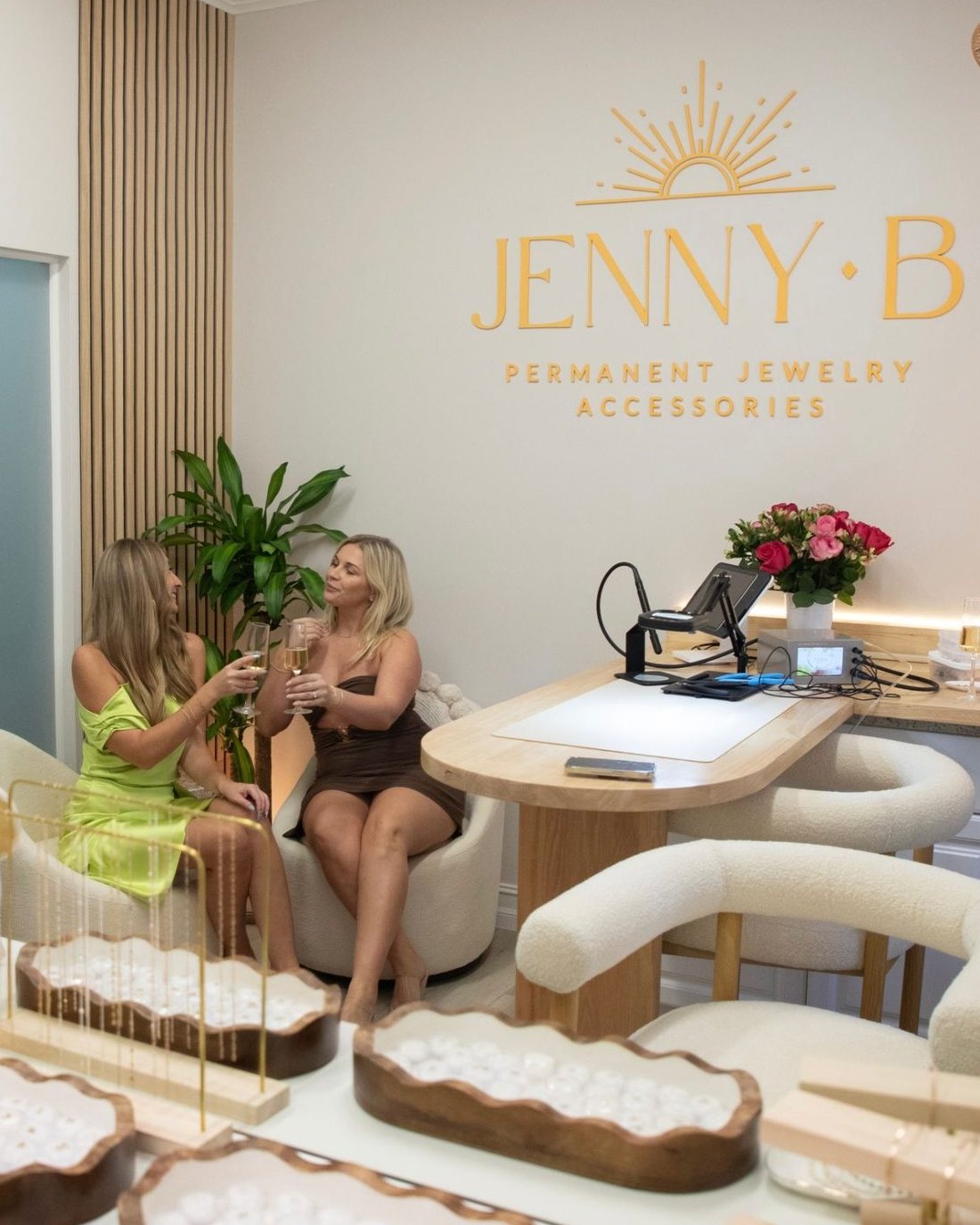 Friends celebrating with Champagne in the studio lounge, beside the welding table and the gold Jenny B logo.